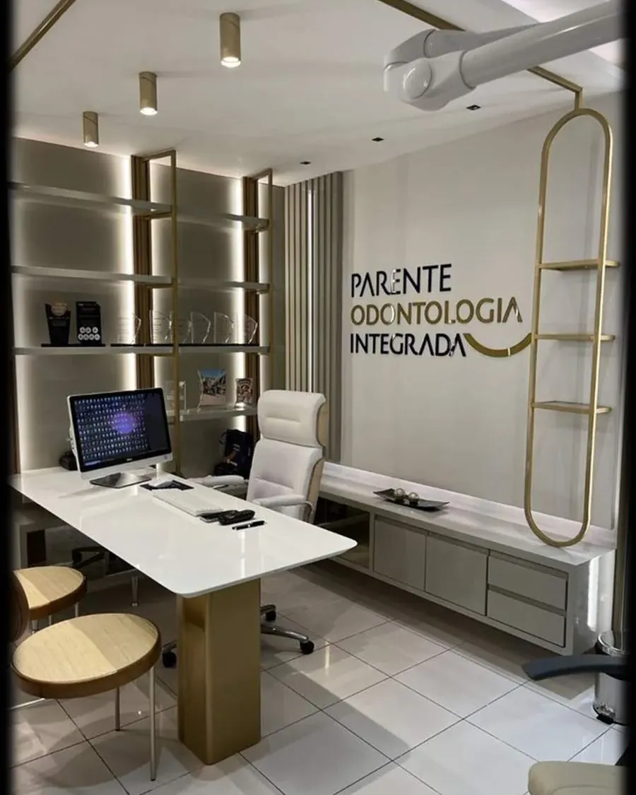 Consultório com bancada branca em L e prateleiras iluminadas
